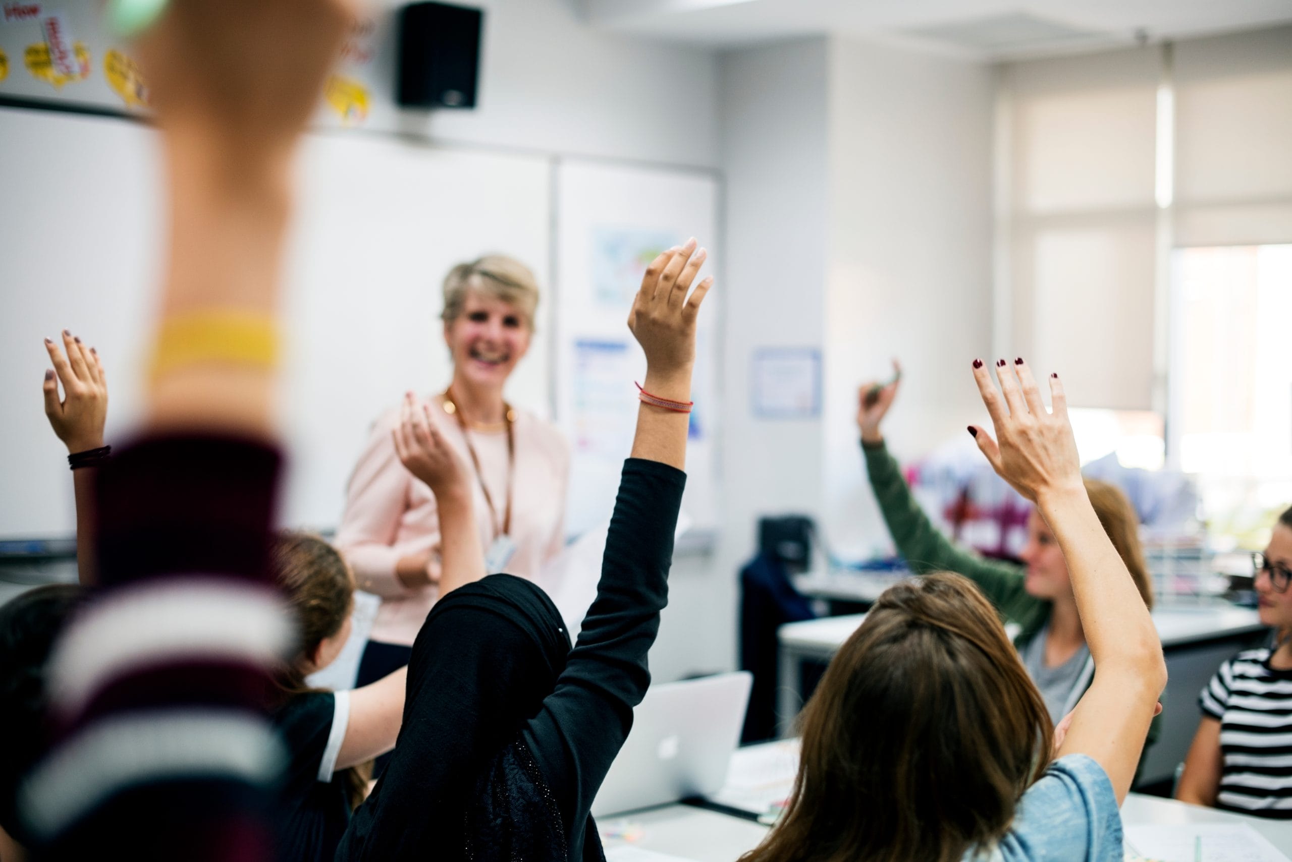 Teacher calling on students with raised hands